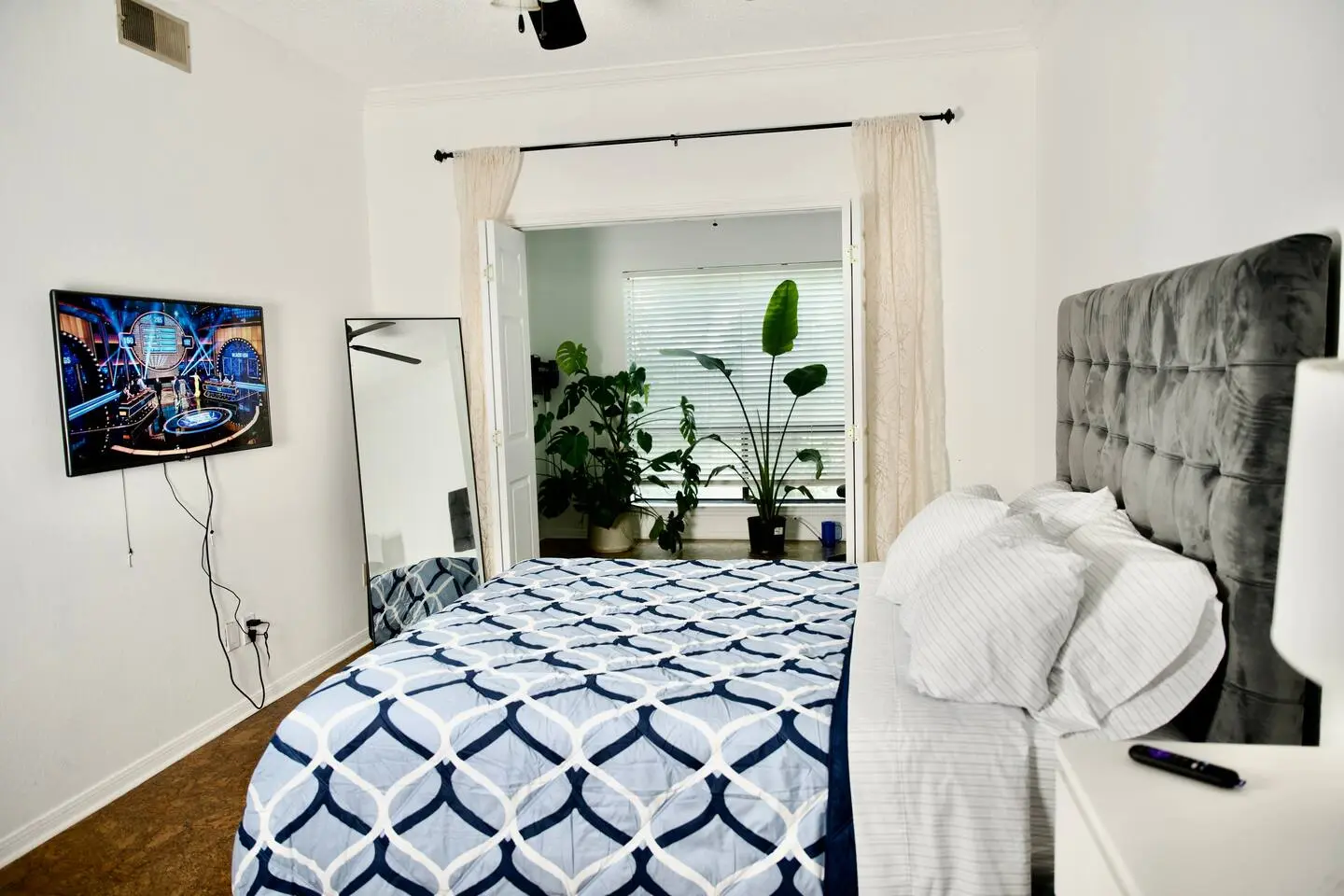 Primary bedroom with queen bed, mirror, and plants