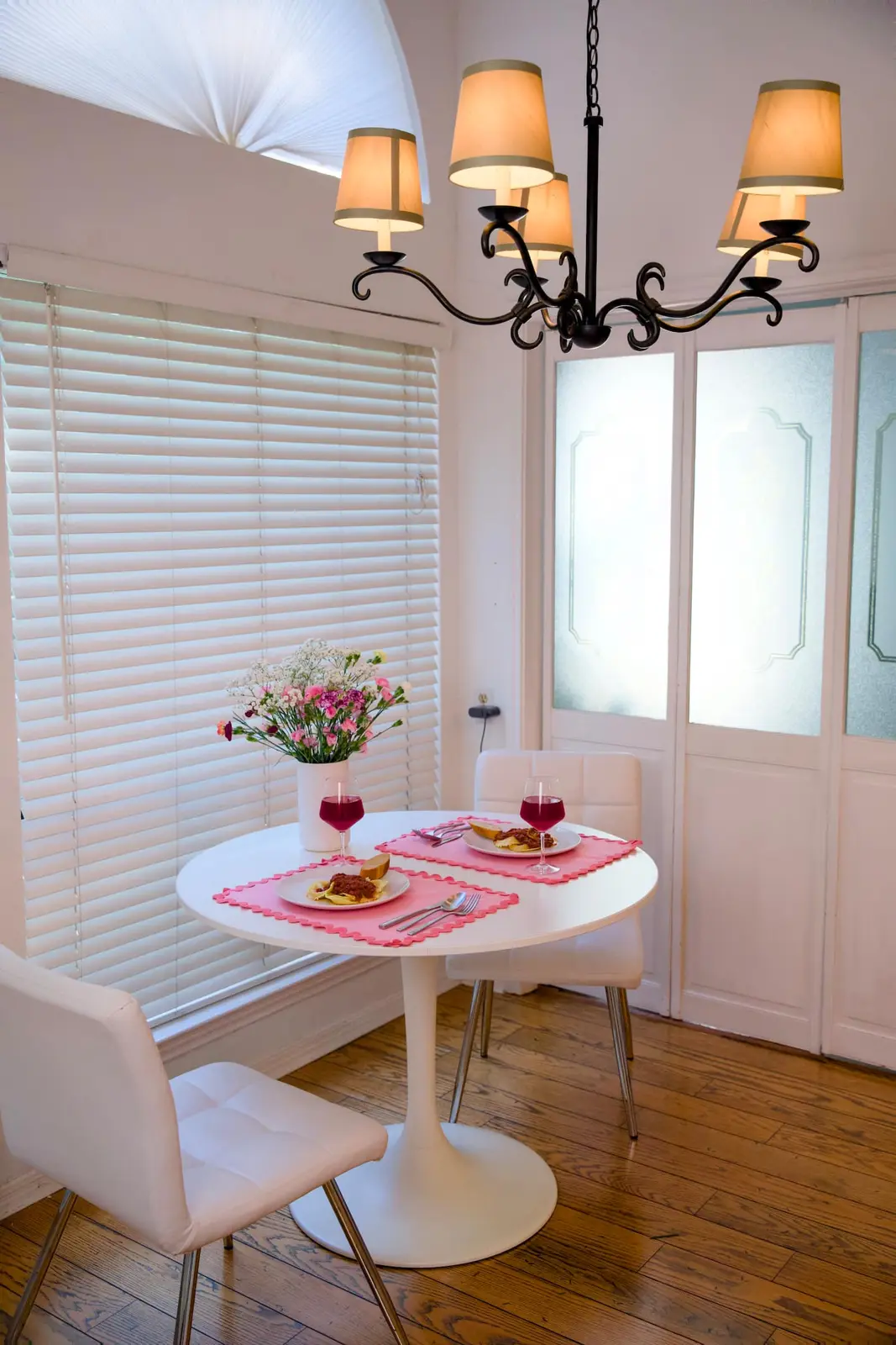 Round dining table by the window under a chandelier