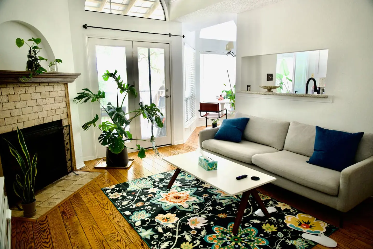 Sunlit living room with a fireplace, gray sofa, and French doors onto the balcony